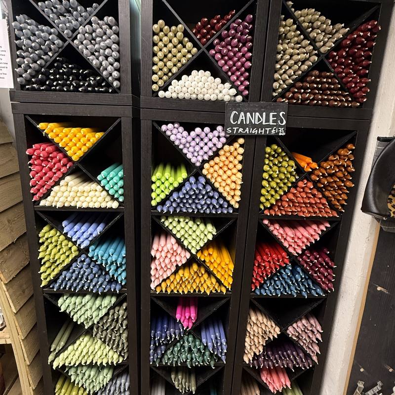 Rack of coloured dinner candles sorted by shade