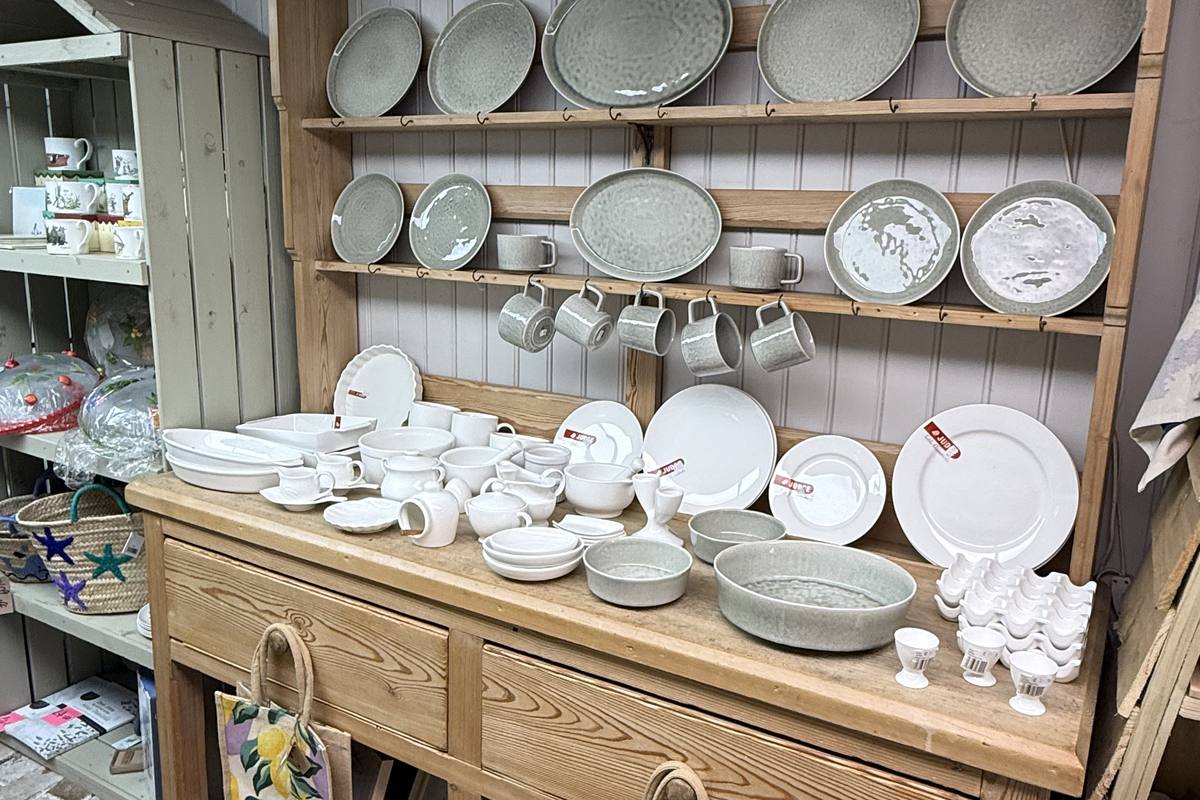 Pine dresser stacked with plates, bowls and jugs, with printed shopping bags on the shelf below
